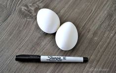 two white eggs sitting on top of a wooden table next to a black marker that says sharpie