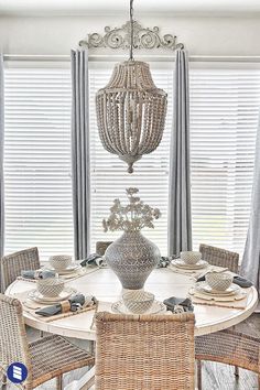 the dining room table is set with place settings for four and has two wicker chairs