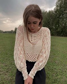 a woman is sitting on the ground with her hands in her pockets and looking down