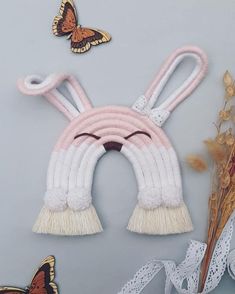 a white and pink wall hanging with two butterflies on top of it next to some flowers