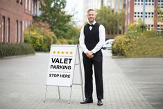 a man standing next to a sign that says valet parking stop here