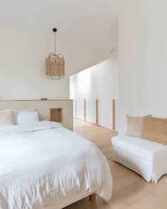 a white bed sitting in a bedroom next to a chair and ottoman on top of a hard wood floor