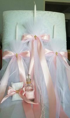 two white candles with pink bows on them