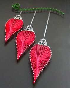 two red heart shaped earrings hanging from a green hook on a black surface with beads