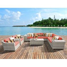 an outdoor furniture set sitting on top of a wooden deck next to the ocean with palm trees in the background