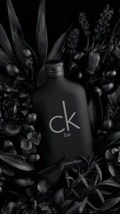 a black and white photo with flowers, leaves and a bottle that says c k