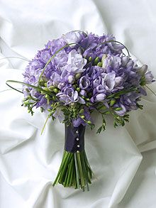 a bouquet of purple flowers sitting on top of a white bed sheet covered in sheets