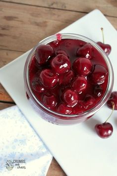 a glass bowl filled with cherries on top of a cutting board