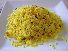 a white plate topped with yellow rice on top of a table