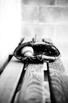 black and white photograph of baseball equipment on wooden bench