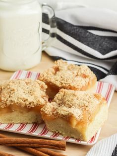 two pieces of cake on a plate next to cinnamon sticks and a jar of milk