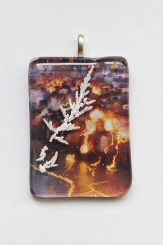 a square glass pendant with leaves on it