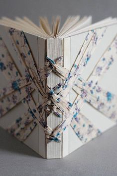 an open book with blue and white flowers on the pages is folded to look like something out of a book