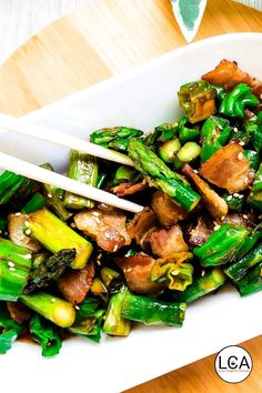 a white bowl filled with stir fry vegetables and chopsticks on top of it