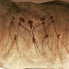 three people holding hands in front of a cave painting