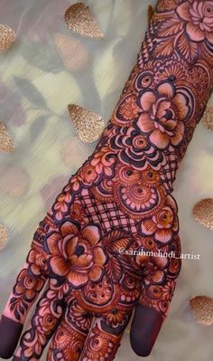 the hand is decorated with henna designs and flowers on it's palm,