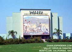 an advertisement on the side of a building in front of palm trees and buildings with mountains behind it