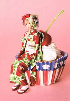 a doll sitting on top of a cupcake