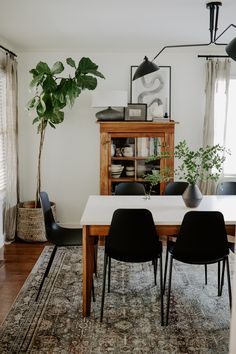 a dining room table with black chairs and a rug