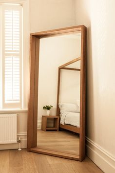 a mirror sitting on top of a wooden floor next to a window