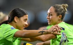 two women in green shirts holding tennis racquets on top of each other