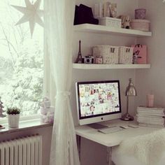 a desk with a computer on top of it in front of a window next to a radiator