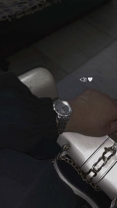 a person is holding a white purse with chains on it and wearing a wrist watch