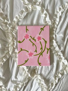 a pink and green painting on a white bed with ruffles in the background