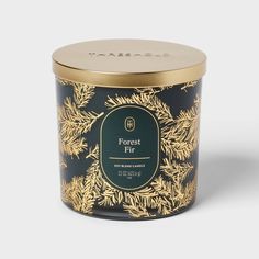 the forest fir candle is in a black and gold tin