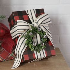 a christmas present wrapped in plaid with a wreath on top