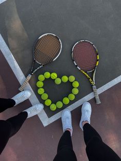 two tennis racquets and some balls on a court with the word love spelled out