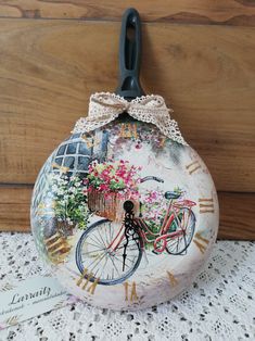 a decorative clock with a bicycle painted on it's face and flowers in the basket