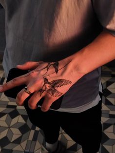 a person with a bird tattoo on their hand