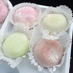 four different colored pastries in white trays on black table top, one pink and one green