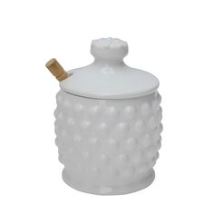 a white ceramic sugar jar with a wooden handle and lid in the shape of a bubble pattern