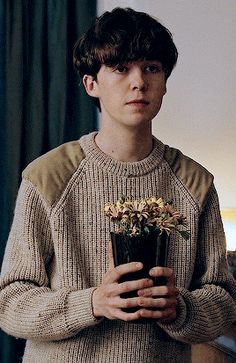 a young man holding a potted plant in his hands