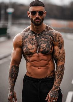 a man with tattoos on his chest and no shirt is walking down the street while wearing sunglasses