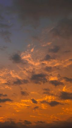 an airplane is flying high in the sky at sunset with clouds and sun going down