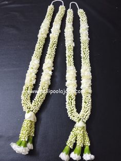 two necklaces with white flowers and green leaves on black background, one is made out of beads