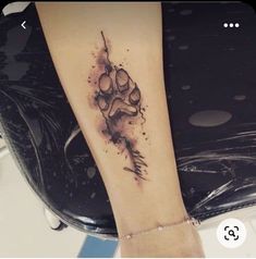 a tattoo on the arm of a woman with a dog paw and watercolors