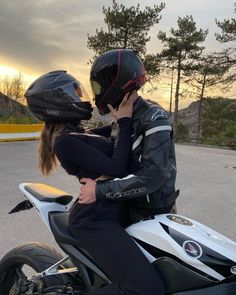 a man and woman are sitting on a motorbike while the sun is setting