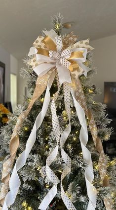 a christmas tree decorated with white and gold ribbons