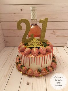 a cake that has some strawberries on it with a bottle of wine in the background