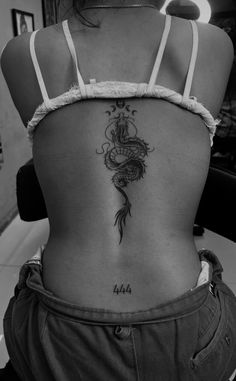 the back of a woman's stomach with a tattoo design on her left side