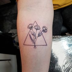 a small triangle tattoo with flowers on the left arm and an arrow in the middle