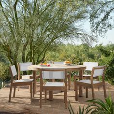 an outdoor table with white chairs around it