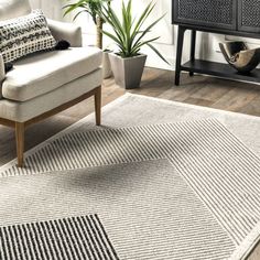 a living room area with a chair, rug and potted plant