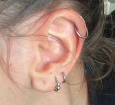 a close up of a person's ear with two small hoops on it