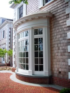 an arched window on the side of a brick building in front of a red brick sidewalk