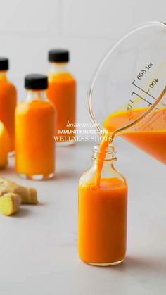 an orange liquid being poured into a glass bottle